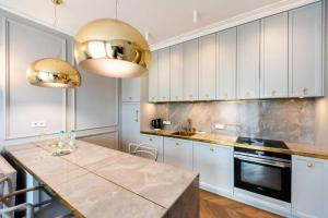 een keuken met witte kasten en een marmeren aanrecht bij Luxury Garden Apartment in Warschau