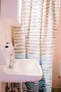 ein Bad mit einem Waschbecken und einem Duschvorhang in der Unterkunft La Playa Suites 1 in Periyiálion