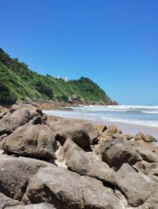 um grupo de rochas numa praia perto do oceano em Praia Tombo Guarujá no Guarujá