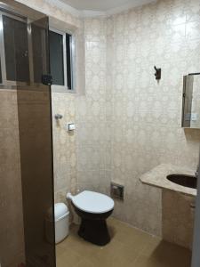 a bathroom with a toilet and a sink at Praia Tombo Guarujá in Guarujá