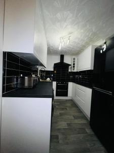 Ensuite Luxury Bedroom In Purfleet في بورفليت: مطبخ به كونترات وأدوات بيضاء وسوداء