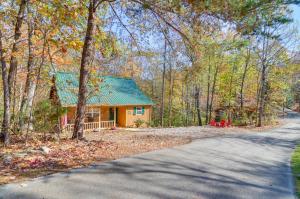 una casa con techo verde en el bosque en Burnside Resort Cabin with Hot Tub and Outdoor Spots!, en Burnside