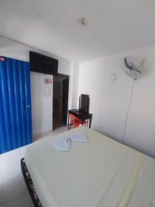 a bedroom with a white bed and a blue door at Hotel Guaipa in Melgar
