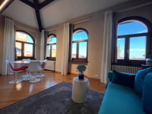 uma sala de estar com um sofá, cadeiras e janelas em Piazza Erbe Lodge em Verona