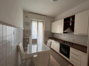 een keuken met witte kasten en een tafel en stoelen bij [Centro] Lussuoso Appartamento in Bergamo