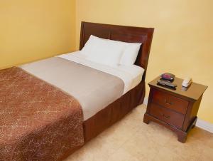 a bedroom with a bed and a nightstand with a bed sidx sidx at El Patio Inn in Los Angeles