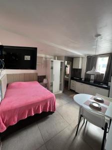 a bedroom with a pink bed and a table at STUDIO 303 | WIFI 600MB | RESIDENCIAL JC, um lugar para ficar. in Belém