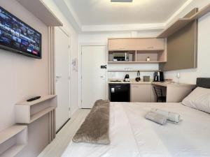 a bedroom with a large white bed and a kitchen at Start - Vila Izabel in Curitiba