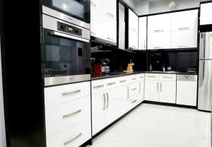 eine Küche mit weißen Schränken und Küchengeräten aus Edelstahl in der Unterkunft Paradise apartments in Sarandë