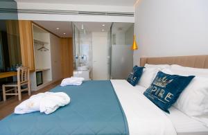 a bedroom with a large bed with blue and white pillows at Empire Beach Resort ADULTS ONLY in Dhërmi