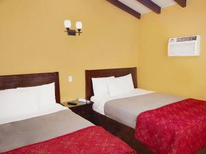 a hotel room with two beds and a red blanket at El Patio Inn in Los Angeles