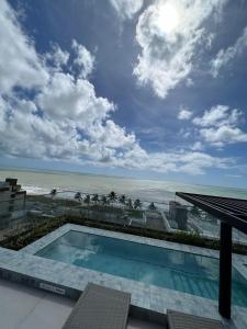 a swimming pool with a view of the ocean at Loft Luxo para 4 pessoas vista mar in Cabedelo