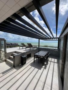a patio with a table and benches and the ocean at Loft Luxo para 4 pessoas vista mar in Cabedelo