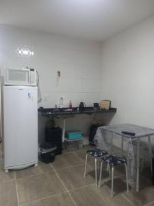 uma cozinha com uma mesa e um frigorífico branco em Casa em Unamar, Cabo Frio - com piscina privativa em Cabo Frio