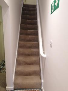 a staircase with brown carpeted stairs in a house at Great Home of Relaxations in Stoke on Trent