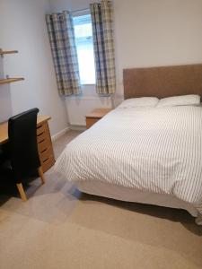 a bedroom with a bed and a desk and a window at Great Home of Relaxations in Stoke on Trent