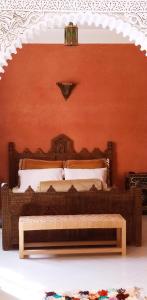 1 dormitorio con 1 cama con pared de color naranja en maison d'hôtes Le petit jardin Marrakech en Marrakech