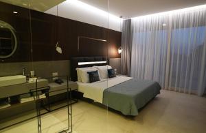 a bedroom with a bed and a sink and a mirror at Empire Beach Resort ADULTS ONLY in Dhërmi