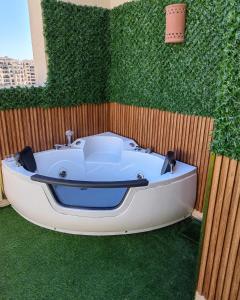 Cordoba suites Penthouse with private open air Jacuzzi في الغردقة: حوض استحمام أبيض جالس أمام جدار أخضر