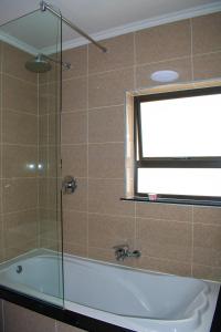 ein Bad mit einer Badewanne und einem Fenster in der Unterkunft Candymoore apartment in Sandton