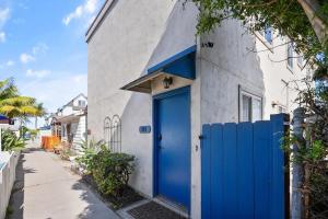 a blue door on the side of a white building at Mission Bay Condo - Steps to Sand, Dining, AC, Parking & Shops! in San Diego