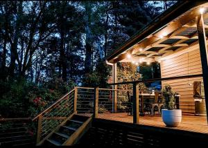 a wooden deck with a patio with a table and lights at Romantic Getaway - 2 luxe outdoor baths in Mount Macedon