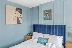 a bedroom with blue walls and a bed with a blue headboard at Lovely 2 Bedroom House with Parking in Loughborough