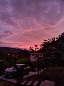 een auto geparkeerd op een oprit bij zonsondergang bij La Marujita villa de campo in Puerto Quito