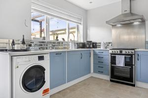 cocina con armarios azules, lavadora y secadora en Lovely 2 Bedroom House with Parking, en Loughborough