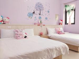 dwa łóżka w sypialni z różowymi ścianami i kwiatami na ścianie w obiekcie 一宿來民宿 w mieście Fengping