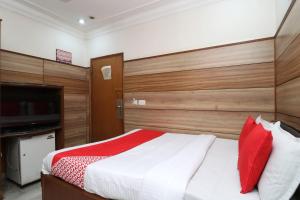 um quarto com uma cama com almofadas vermelhas e uma televisão em OYO Flagship Vivek International Hotel em Jalandhar
