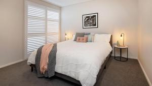 a bedroom with a large white bed with a window at Alpine Snow Angels Retreat in Jindabyne