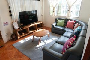 a living room with a leather couch and a television at Baan Ragang : Cozy Entire House in Old Chiang Mai in Chiang Mai