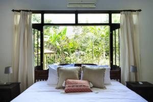 een bed met kussens voor een raam bij Spacious 1bd Villa Suite in Penestanan in Ubud
