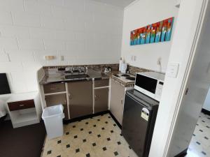 Il comprend une petite cuisine équipée d'un évier et d'une cuisinière. dans l'établissement Motel Villa Del Rio, à Whangarei