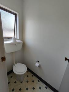 een badkamer met een toilet, een wastafel en een raam bij Motel Villa Del Rio in Whangarei