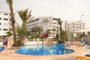 une grande piscine avec des palmiers et des bâtiments dans l'établissement Atlantic Palm Beach, à Agadir