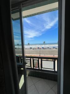 a view of the beach from a room with a window at Apartamento pé na areia de frente para o mar in Mongaguá