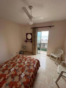 um quarto com uma cama e uma janela com vista em Apartamento pé na areia de frente para o mar em Mongaguá
