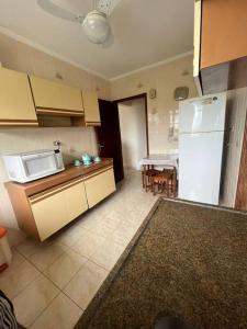 cocina con nevera blanca y mesa en Apartamento pé na areia de frente para o mar, en Mongaguá