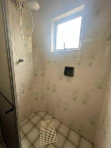 La petite salle de bains est pourvue d'une douche et d'une fenêtre. dans l'établissement Apartamento pé na areia de frente para o mar, à Mongaguá