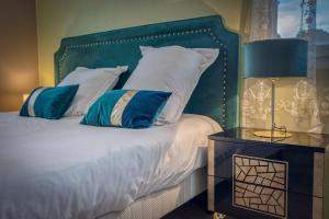 Schlafzimmer mit einem Bett mit einem grünen Kopfteil und Kissen in der Unterkunft Le Donjon Bleu - Calme / Montagne /Ski 