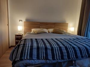 a bedroom with a bed with a blue striped comforter at Departamentos Amoblados Paz, estudio en Pucón,Camino al Volcán! in Pucón