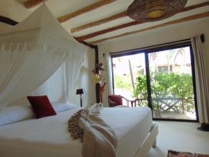 a bedroom with a white bed and a large window at LUV Tulum in Tulum