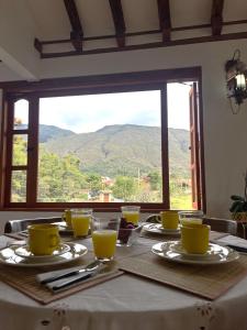 uma mesa com copos amarelos e vista para as montanhas em Refugio Khalma de la Montaña em Villa de Leyva