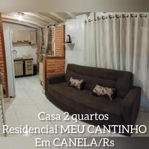 a living room with a brown couch and a kitchen at RESIDENCIAL MEU CANTINHO in Canela
