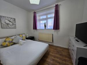 1 dormitorio con 1 cama blanca grande y TV en Globe Rooms, en Londres