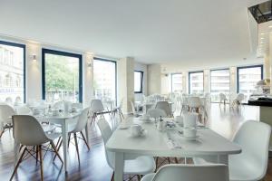 a restaurant with white tables and chairs and windows at Cityhotel am Thielenplatz in Hannover