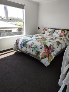 1 dormitorio con 1 cama con colcha de flores en Modern House near Motuoapa Tongariro Crossing fishing skiing, en Turangi