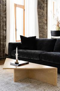 een woonkamer met een zwarte bank en een houten salontafel bij Place Royale by Luxury In Transit in Montreal